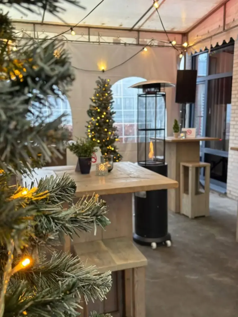 Tent met lichtsnoeren, terrasheater, statafel en kerstboom