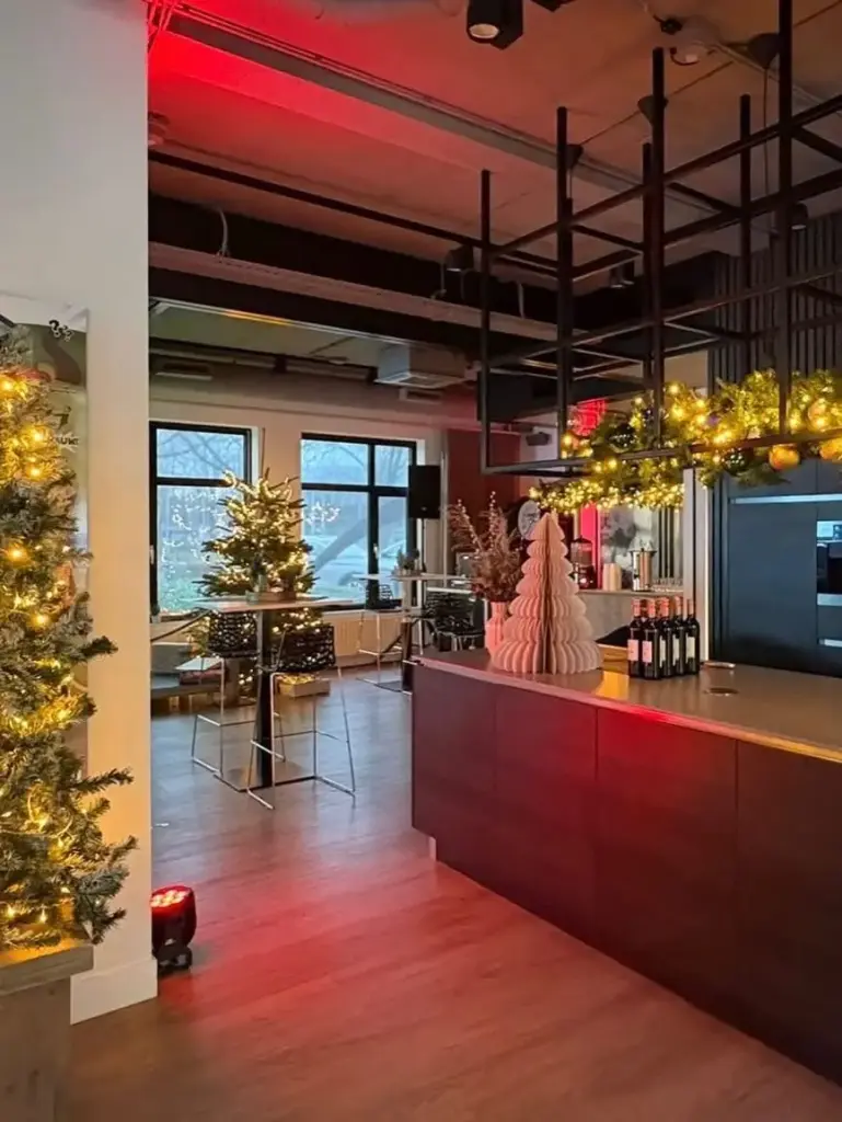 Bedrijfsruimte in kerstsfeer met rode sfeerverlichting, verlichte kerstbomen en bar